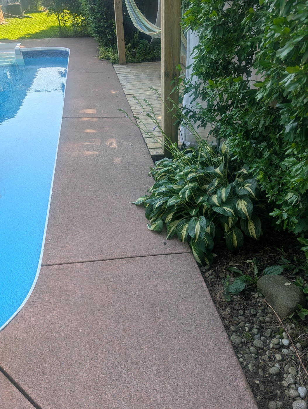 Same concrete walkway beside pool after pressure washing, clean and uniform
