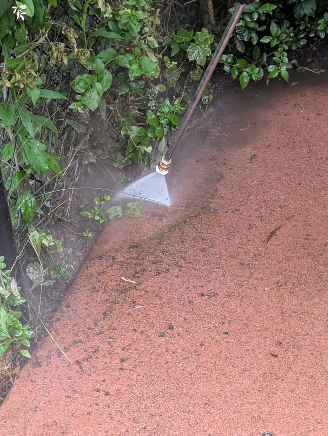 Pressure washing wand cleaning a pool-side concrete walkway